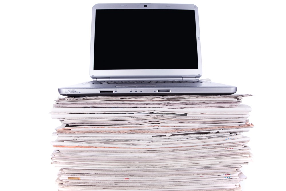 Laptop on top of a stack of files before digital backups are made of the physical documents.